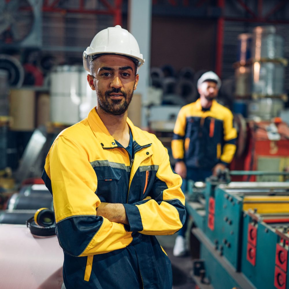 Portrait of Smiling Professional Industry Engineer standing and looking camera, Worker Wearing Safety Uniform and Hard Hat at factory. Machine maintenance technician operation concept.