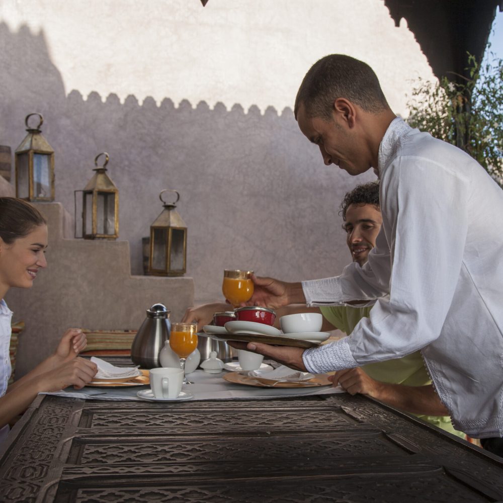 Waiter serving young couple breakfast, Marrakesh, Morocco